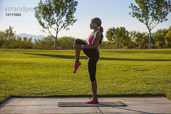 Seitenansicht einer Frau  die auf einem Grasfeld Yoga praktiziert