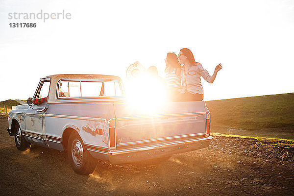 Freunde fahren bei Sonnenuntergang im Pick-up