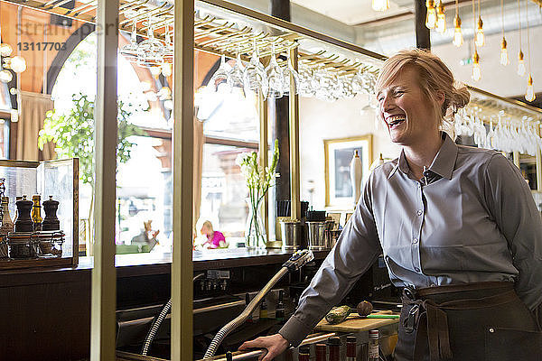 Fröhlicher Barkeeper steht am Tresen in Bar