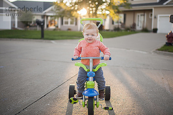 Porträt eines süßen kleinen Jungen auf einem Dreirad auf der Straße