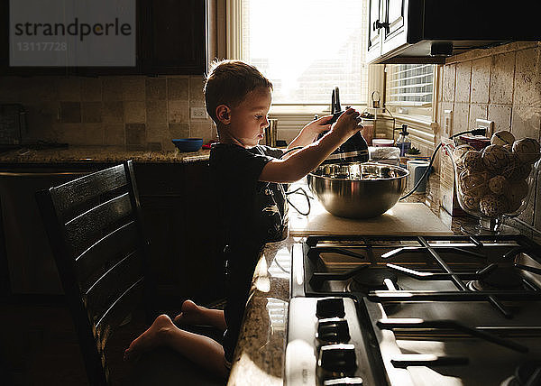 Seitenansicht eines Jungen  der zu Hause in der Küche Essen zubereitet