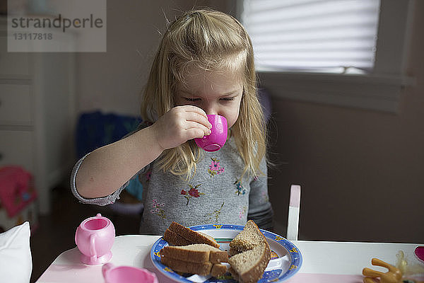Nahaufnahme eines Mädchens  das mit Spielzeug spielt  während es zu Hause Brot isst