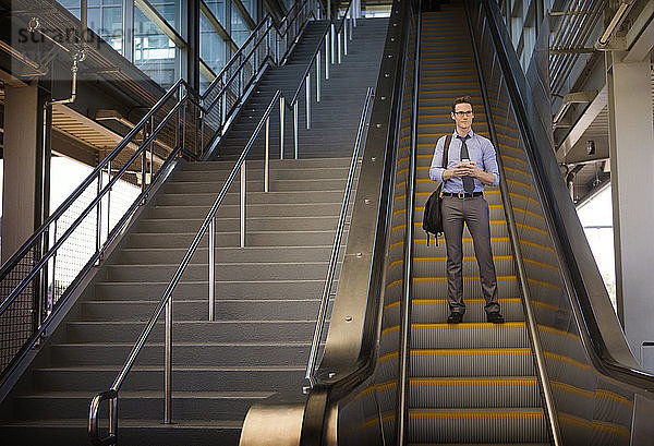 Niedriger Blickwinkel eines auf der Rolltreppe stehenden Geschäftsmannes