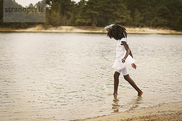 Seitenansicht eines als Engel verkleideten Mädchens beim Spaziergang am See