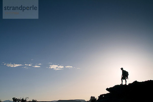 Silhouette eines Mannes  der auf einem Berg gegen den Himmel steht