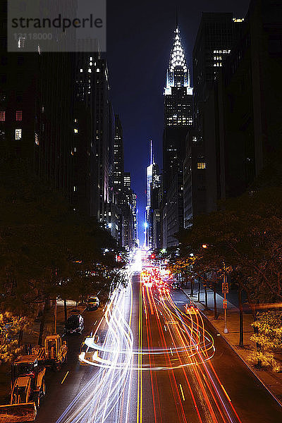 Lichtspuren auf Stadtstraßen durch beleuchtete Gebäude bei Nacht