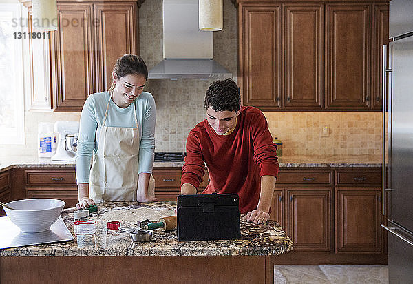 Glückliche Geschwister benutzen Laptop-Computer in der Küche zu Hause