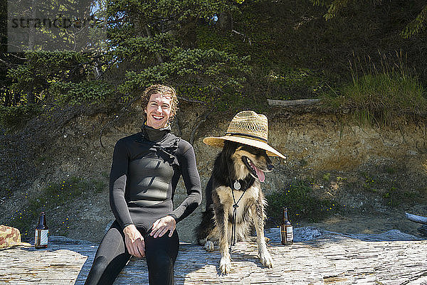 Porträt eines glücklichen Mannes mit Hund am Strand