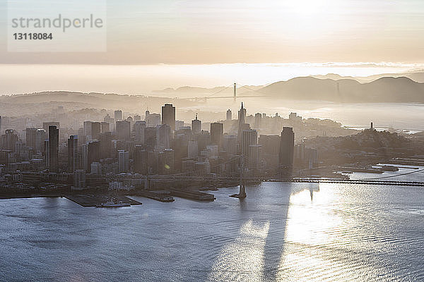 Hochwinkelansicht der Oakland Bay Bridge über das Meer in der Stadt bei Sonnenaufgang