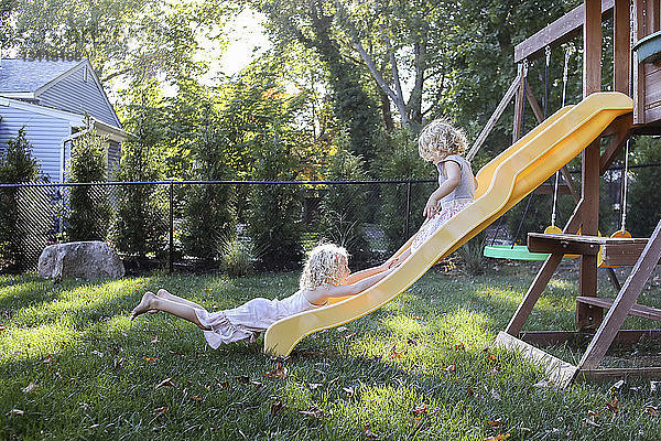 Schwestern spielen auf der Rutsche auf dem Spielplatz