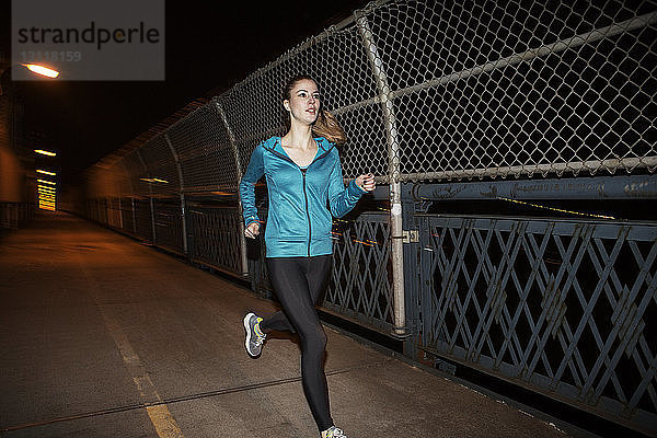 Junge Frau joggt nachts auf der Brücke