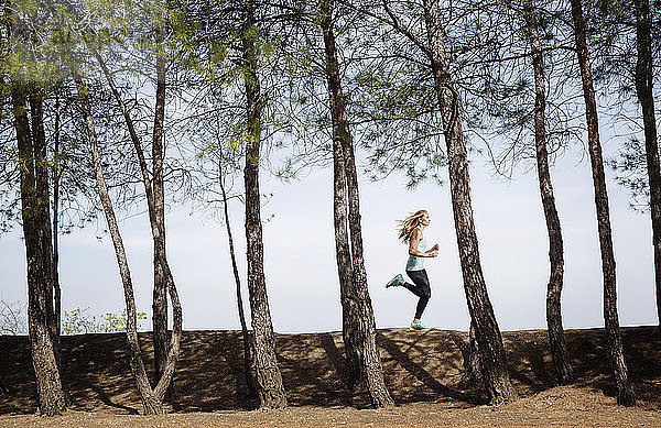 Seitenansicht einer Frau  die auf einem Feld inmitten von Bäumen läuft