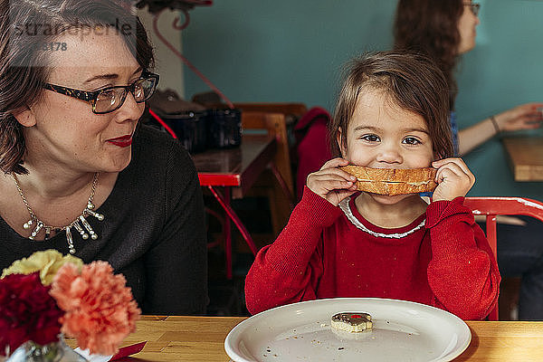 Mutter beobachtet Tochter beim Brotessen am Restauranttisch