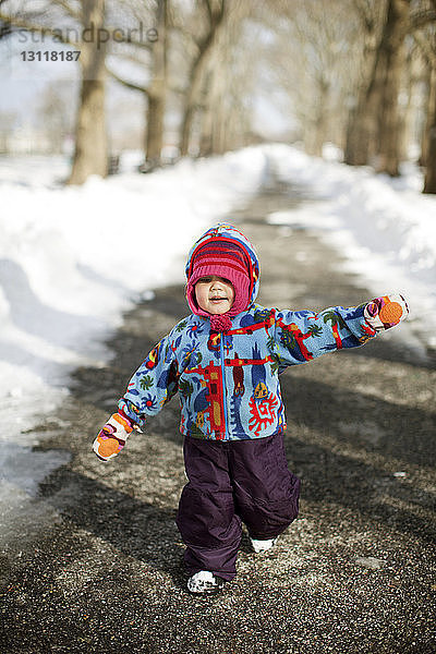 Süßes Mädchen läuft auf der Straße inmitten von Schnee