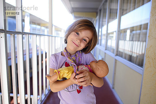 Porträt eines glücklichen Mädchens mit einer Puppe im Korridor
