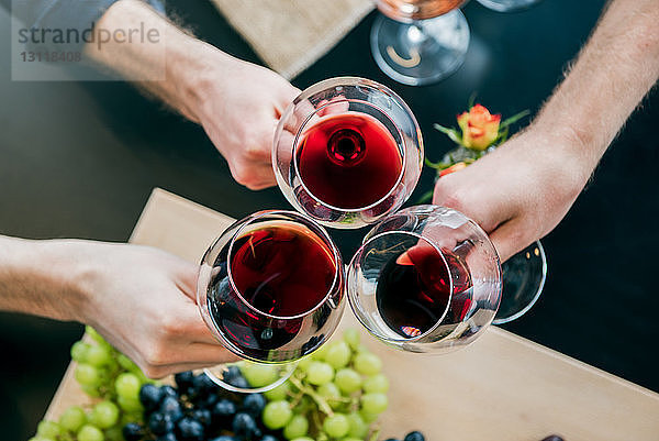 Abgehackte Hände männlicher Freunde stoßen im Verkostungsraum auf Wein an