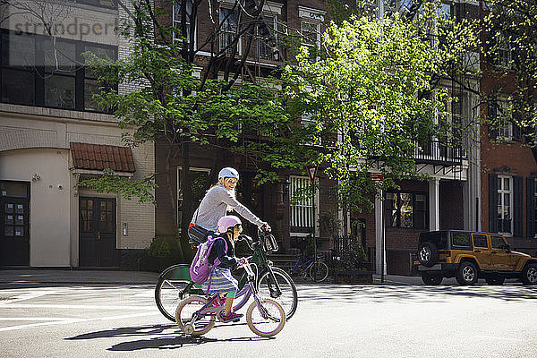 Seitenansicht von Mutter und Tochter beim Fahrradfahren auf der Straße