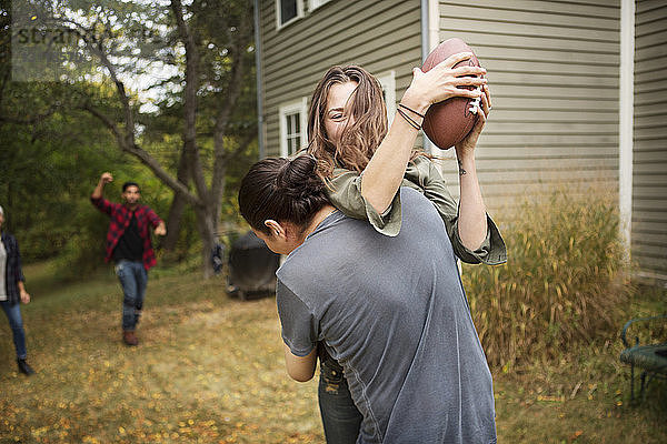 Paar spielt mit Freunden auf dem Feld Fussball