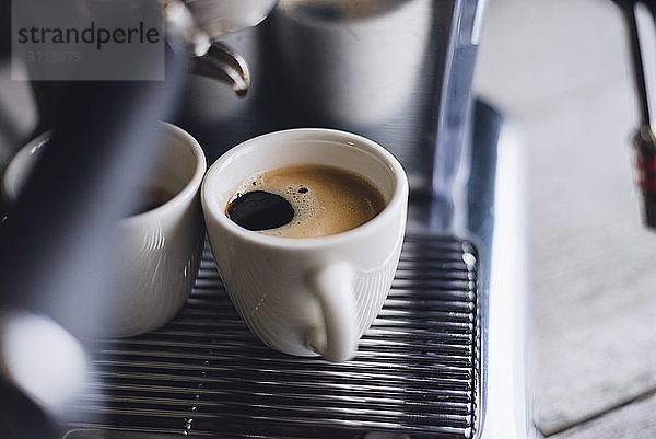 Hochwinkelansicht von Kaffeetassen auf Espressomaschine