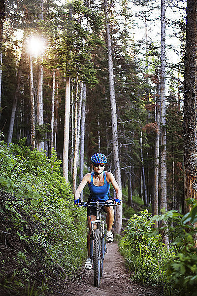 Weibliche Athletin beim Radfahren auf Feld im Wald