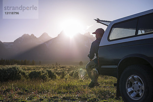 Mann schaut weg  während er auf einem Geländewagen im Grand-Teton-Nationalpark sitzt