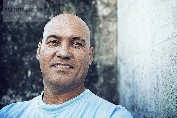 Bildnis eines Mannes in blauem T-Shirt an der Wand stehend