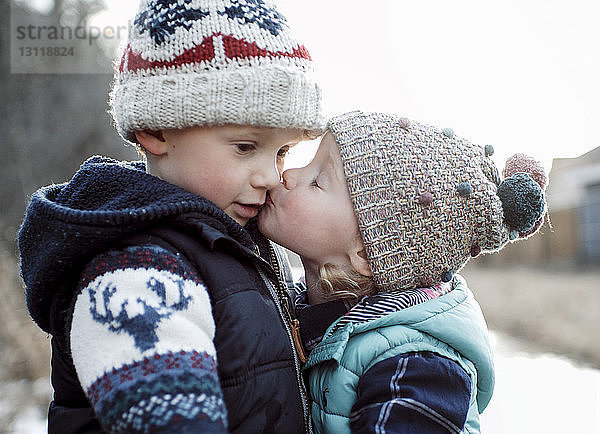 Liebende Schwester küsst Bruder im Winter