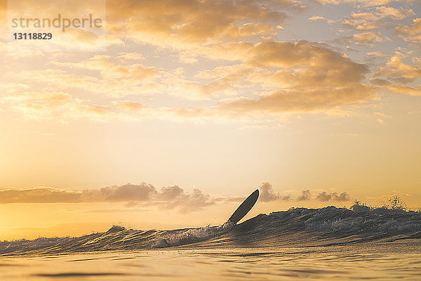 Surfbrett auf dem Meer gegen den Himmel bei Sonnenuntergang