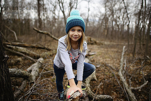 Porträt eines selbstbewussten Mädchens  das sich im Wald an einen getrockneten Ast lehnt