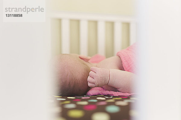 Nahaufnahme eines in einem Kinderbett schlafenden Mädchens durch das häusliche Geländer gesehen