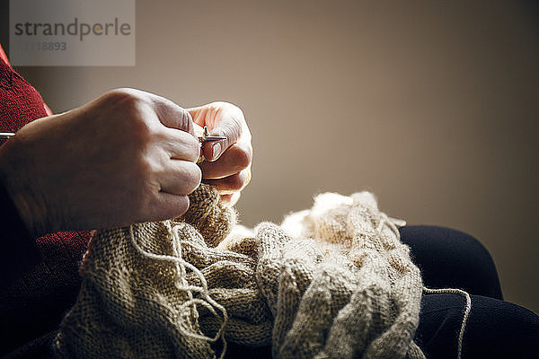 Mittelteil einer älteren Frau  die zu Hause strickt