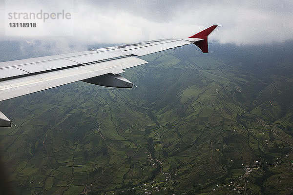 Ausschnittsbild eines Flugzeugs  das über eine grüne Landschaft fliegt