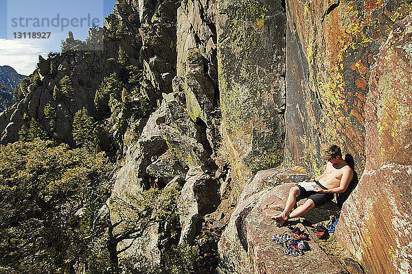 Bergsteiger liest Buch  während er auf dem Berg sitzt