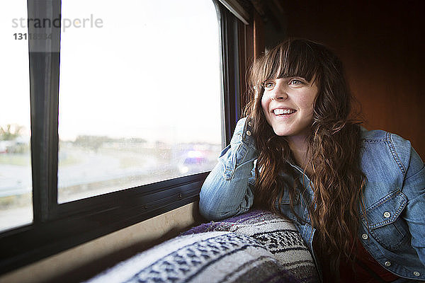Frau lächelt  während sie im Wohnmobil am Fenster sitzt
