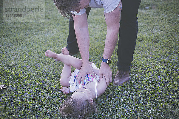 Schrägaufnahme eines glücklichen Vaters und einer glücklichen Tochter beim Spielen im Garten