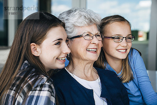 Glückliche Großmutter und Enkelinnen schauen auf der Veranda weg