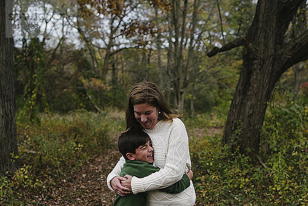 Glückliche Mutter umarmt Sohn  während sie auf dem Feld im Park steht