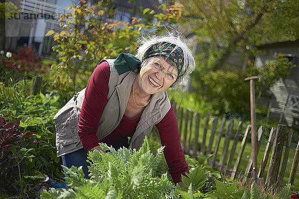Porträt einer fröhlichen älteren Frau bei der Gartenarbeit im Hinterhof