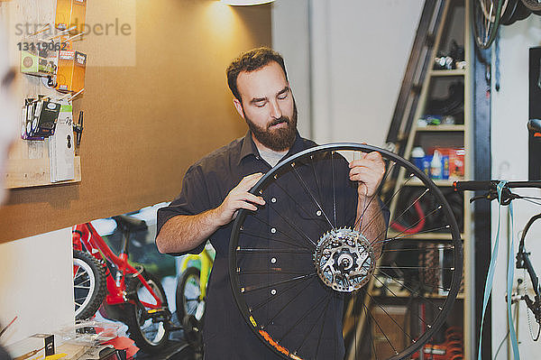 Männlicher Mechaniker repariert Fahrradreifen in Werkstatt