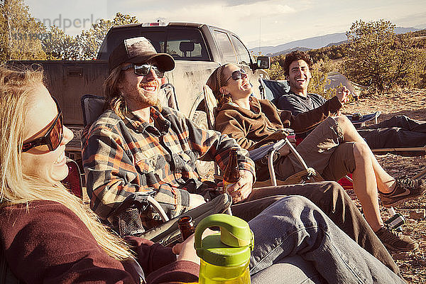 Freunde genießen  während sie sich auf dem Campingplatz am Geländewagen ausruhen
