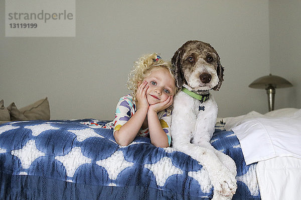 Porträt eines Mädchens mit Hund auf dem Bett an der Wand liegend