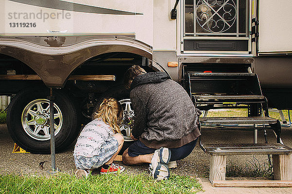 Rückansicht von Vater und Tochter bei der Reifenreparatur