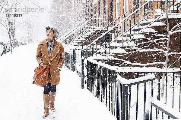 Frau schaut weg  während sie bei Schneefall auf schneebedecktem Feld geht