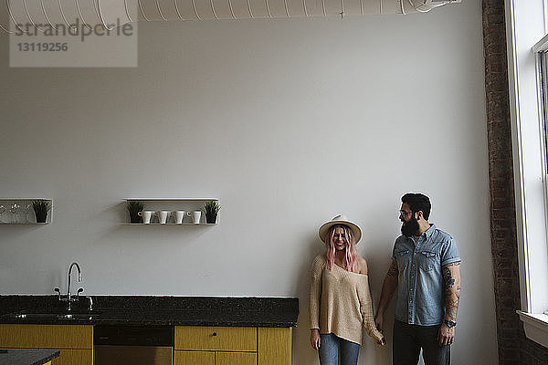 Glückliches Paar  das zu Hause in der Küche an der Wand steht