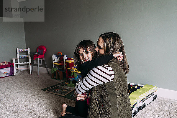 Seitenansicht einer glücklichen Mutter  die ihre Tochter zu Hause umarmt