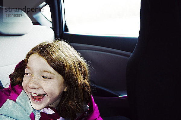 Glückliches Mädchen sitzt am Fenster im Auto