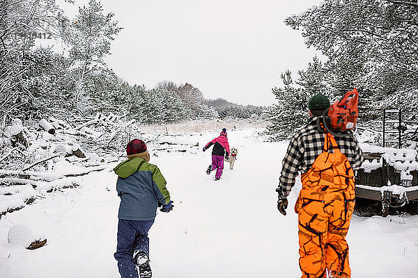 Rückansicht der Familie beim Geniessen mit Pudel auf schneebedecktem Feld gegen den Himmel