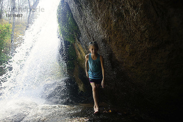 Mädchen in voller Länge an Wasserfällen entlang