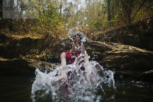 Junge spritzt Wasser beim Genießen im Fluss