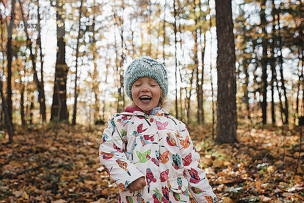 Süßes Mädchen mit geschlossenen Augen lacht  während sie im Wald steht